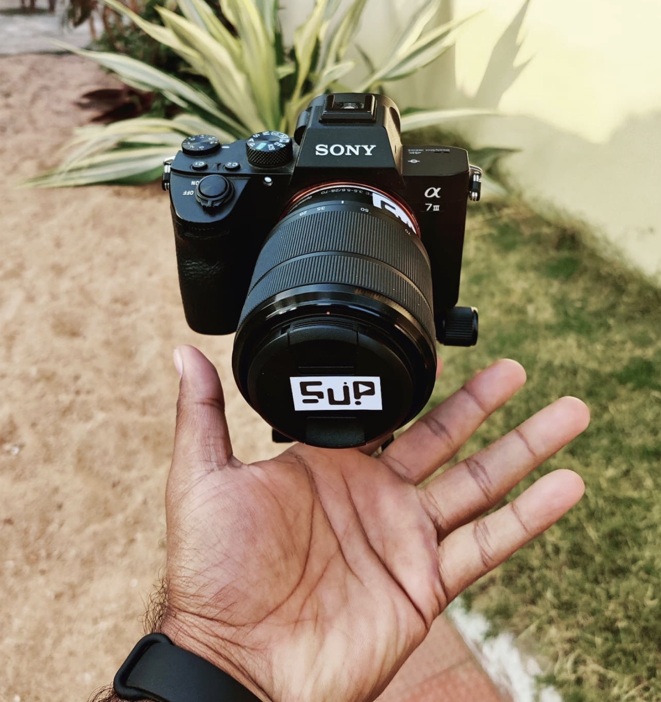 A Sony camera with an S-UP label held outdoors